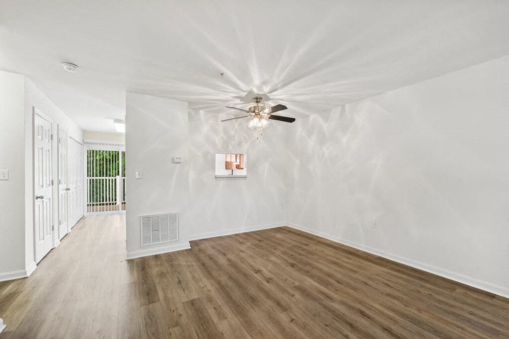 a living room with white walls and a ceiling fan